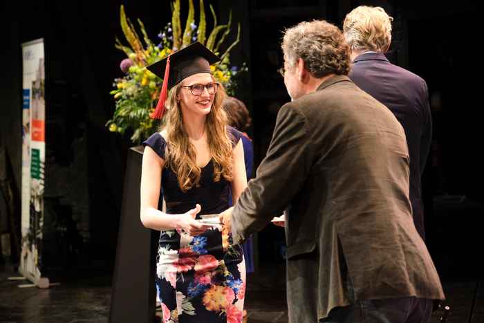 AUC student walking on stage and receiving ceremonial certificate