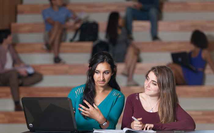 Students looking at the admissions requirements on a laptop