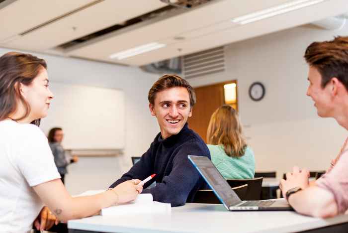 Student smiling turning around in seat in a group with two others