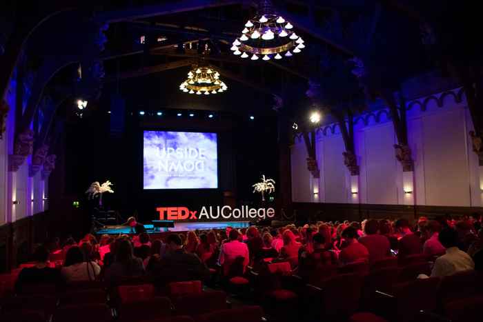 Wide-angle picture of a stage with the AUCollege TEDx letters