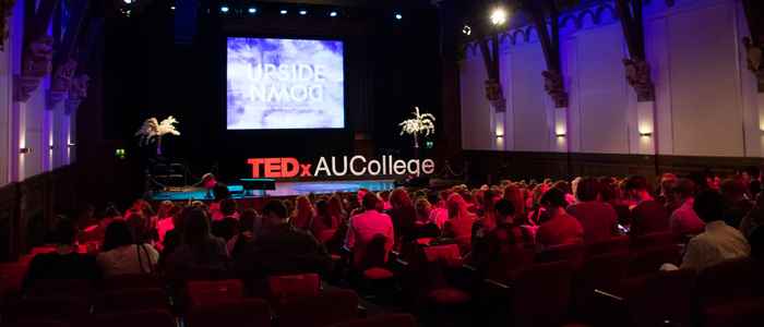 Wide-angle picture of a stage with the AUCollege TEDx letters