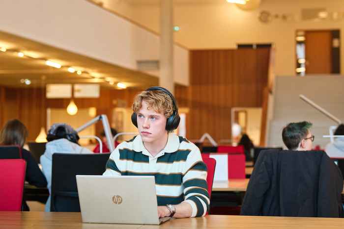 Student seated at desk at this his laptop