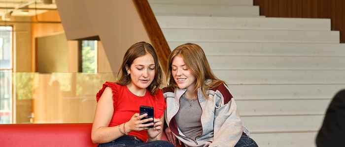 AUC students talking to each other on a couch looking at a phone