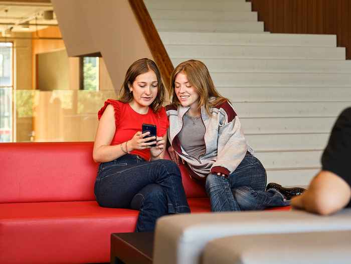 AUC students talking to each other on a couch looking at a phone